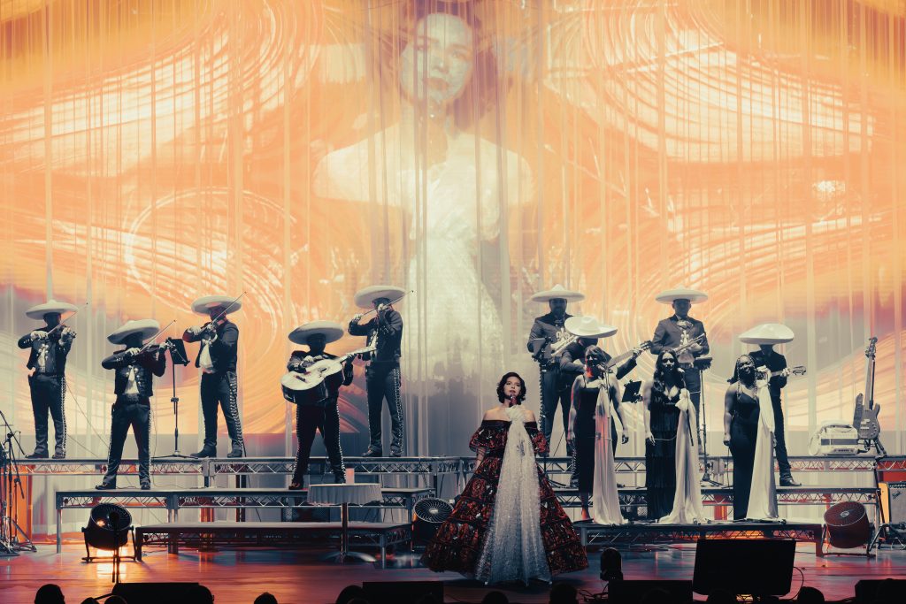 Ángela Aguilar cantando en el escenario del Dolby Theatre con mariachi y coristas, frente a una proyección visual durante su Libre Corazón Tour.
